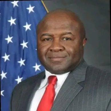 A man in a suit and tie standing next to an american flag.