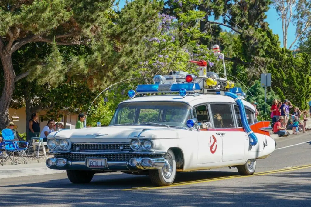 A ghostbuster car is driving down the street in a parade.